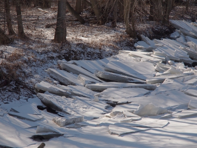 [Large chunks of ice overlapping each other on the riverbanks. River is completely ice covred.]